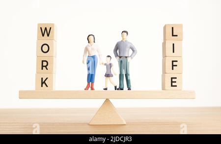 Équilibre entre concept de vie et de travail. Figurines de famille et blocs de bois avec mot sur la seesaw Banque D'Images