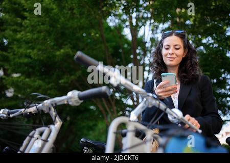 Femme d'affaires avec vélo assis et utilisant un smartphone. Transport et transport alternatif Banque D'Images