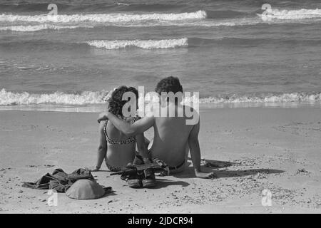 Un soldat israélien est assis avec sa petite amie sur la plage de tel Aviv, se baignant dans la mer, withtelmeer, privé, bottes de soldat, casque d'acier et Uzi sous-mitrailleuse sont écartés mais à portée de main, pendant la guerre du Kippour Yom, la guerre du Kippour entre Israël et les États arabes d'Égypte, La Jordanie et la Syrie ont duré de 6 octobre à 25 octobre 1973, Banque D'Images