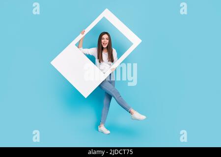 Vue sur toute la longueur du corps de fille attrayante et gaie dansant cadre de maintien ayant l'amusement isolé sur fond bleu clair de couleur Banque D'Images