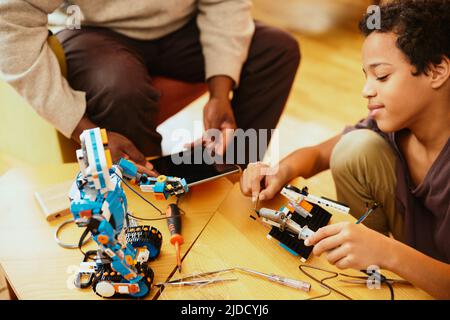 Un grand-père et son petit-enfant construisent un robot à la maison. Banque D'Images