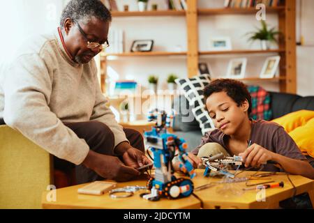 Un petit-père et un petit-fils qui font un robot ensemble à la maison. Formation en robotique et en électronique. Banque D'Images