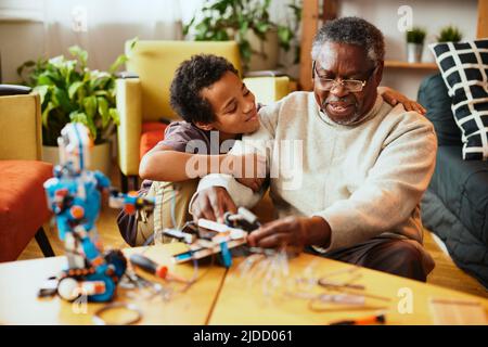 Un grand-père et son petit-enfant construisent un robot à la maison. Banque D'Images