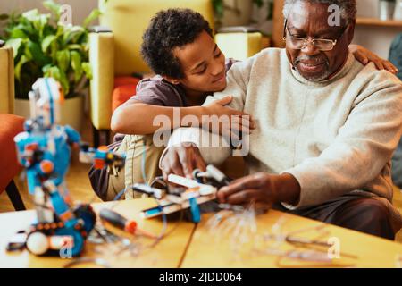 Un grand-père et son petit-enfant construisent un robot à la maison. Banque D'Images