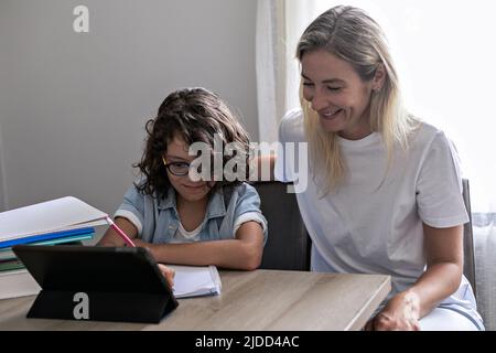 Lunettes de mère et de petit fils étudier en ligne sur tablette à la maison ensemble de la leçon, préparer les devoirs Banque D'Images