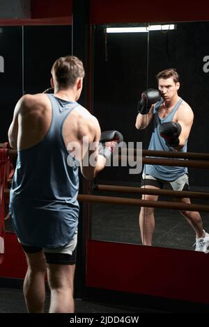 Jeune athlète masculin déterminé s'exerçant à la salle de gym Banque D'Images