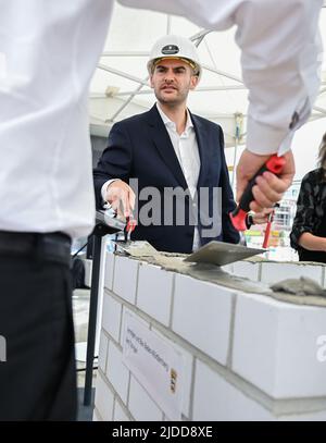 20 juin 2022, Bade-Wurtemberg, Tübingen: Danyal Bayaz (Bündnis 90/Die Grünen), ministre des Finances du Bade-Wurtemberg, briques dans une capsule temporelle lors de la pose cérémonielle de la pierre de fondation du campus d'innovation de la « Cyber Valley » à Tübingen. La « Cyber Valley » est la plus grande coopération de recherche en Europe dans le domaine de l'intelligence artificielle avec des partenaires de la politique, de la science, des affaires et de la société. En plus du nouveau bâtiment Cyber Valley I, qui a été approuvé en 2016, le concept global du site de Tübingen comprend deux autres nouveaux bâtiments. Photo: Bernd Weißbrod/dpa Banque D'Images