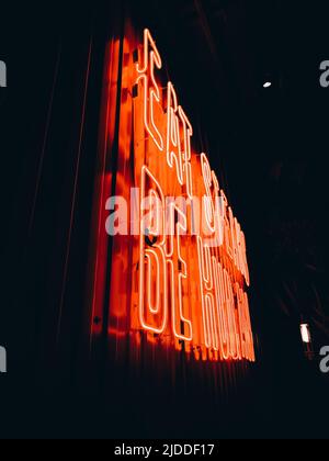 Lettre lumineuse au néon rouge « Eat steaks be Human » sur une photo verticale sombre Banque D'Images