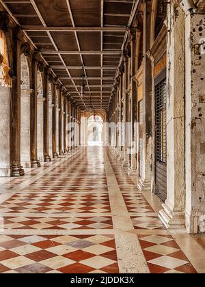 Un long passage à côté du Palais des Doges à Venise est recouvert de carreaux de marbre entre les colonnes en pierre. Banque D'Images