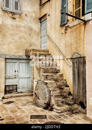 Une cour calme à Bonifacio, juste à côté de la rue principale, comprend un escalier menant à une porte du deuxième étage. Banque D'Images