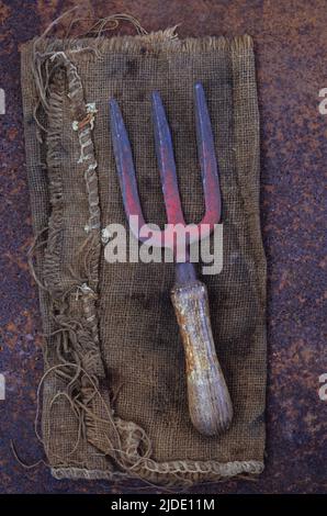 Fourche de jardin bien utilisée reposant sur un sac en toile rouillée Banque D'Images