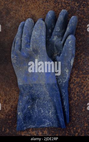 Gants en caoutchouc bleu extra-robustes recouverts de peinture ou de produits chimiques sur une tôle rouillée Banque D'Images