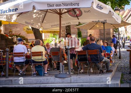 Nuremberg, Allemagne- 15 juin,2022:Un serveur apporte la nourriture et les boissons commandées à une table dans une terrasse. Banque D'Images