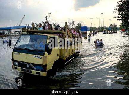 Semarang, Indonésie. 20th juin 2022. Les gens traversent un véhicule dans les eaux d'inondation déclenchées par des marées hautes au port EMAS de Tanjung sur la côte de Semarang, Java central, Indonésie, 20 juin 2022. Credit: Rahman Indra/Xinhua/Alamy Live News Banque D'Images