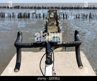 Le guidon de vélo debout sur le bord d'un chemin démoli avec horizon de mer Banque D'Images