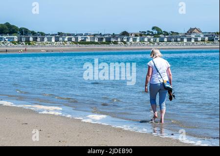 Cranfield, County Down, Royaume-Uni. Lors d'une journée de soleil et de sommets de 20C, de nombreuses personnes ont frappé les plages d'Irlande du Nord. Une femme marche le long du rivage sur Cranfield Beach. Crédit : AG News/Alay Live News Banque D'Images