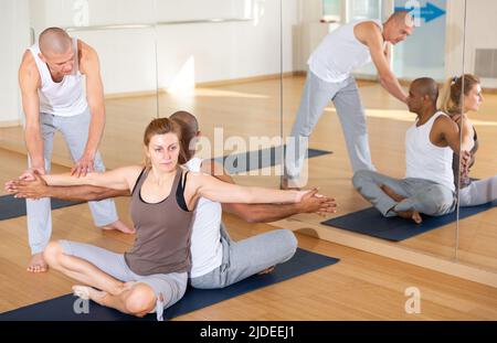 Femme et homme effectuant des exercices de yoga jumelés avec un instructeur Banque D'Images