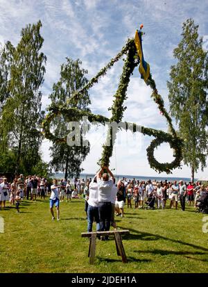 Élever et danser autour d'un maypole lors d'une célébration en milieu d'été en Suède. Banque D'Images