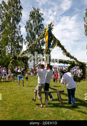 Élever et danser autour d'un maypole lors d'une célébration en milieu d'été en Suède. Banque D'Images