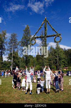 Élever et danser autour d'un maypole lors d'une célébration en milieu d'été en Suède. Banque D'Images