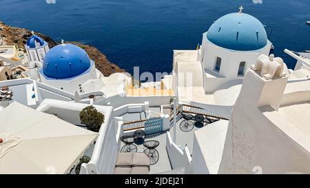 Vue sur l'eau au-dessus des patios et des dômes bleus de l'église dans l'emblématique Oia sur l'île de Santorini Banque D'Images