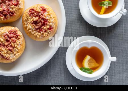 Beignets sucrés sur les assiettes et petites tasses avec thé à la menthe sur la table grise. Petit déjeuner savoureux. Vue de dessus Banque D'Images