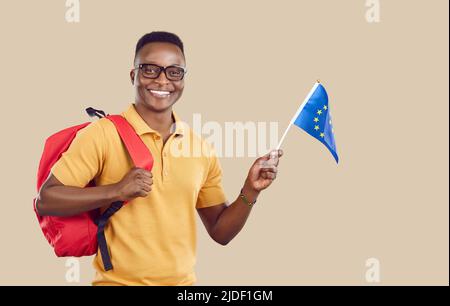 Joyeux étudiant afro-américain avec drapeau de l'Union européenne isolé sur fond beige clair. Banque D'Images