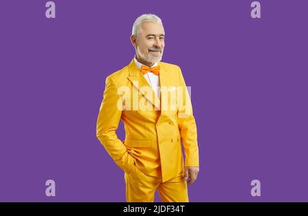 Beau homme portant un élégant costume jaune souriant à l'appareil photo, heureux et riche Banque D'Images