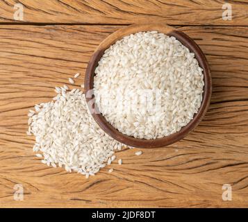 Riz carnaroli risotto cru dans un bol sur table en bois. Banque D'Images