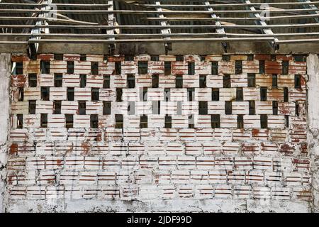 Mur avec des briques exposées, dans la couleur de l'argile, avec une peinture blanche claire déjà décolorée par le temps. Au-dessus il ressemble à la brique creuse et les lattes où t Banque D'Images