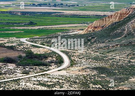 Vue sur la route principale qui traverse le désert de Bardenas Reales. Au loin, deux personnes passent à vélo dans la réserve naturelle. Bardenas Reales, S. Banque D'Images