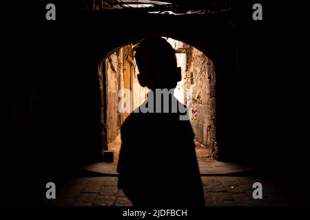 Silhouette d'un jeune garçon méconnaissable, enfant marchant dans la rue dans la vieille ville de Damas, Syrie Banque D'Images