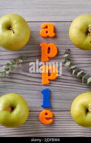 Pomme mot et pommes vertes sur table grise. Vue de dessus de la pose à plat. Banque D'Images