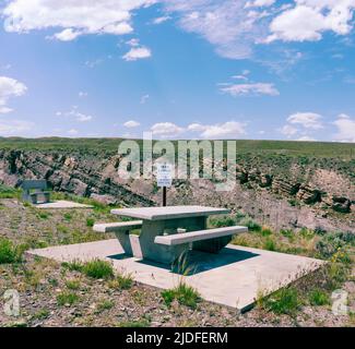 Une table de pique-nique à l'extérieur du parc de Cody, Wyoming, surplombe un vaste espace de terre, de ciel, de nuages et de canyon. Le panneau indique « Trail closed ». Banque D'Images