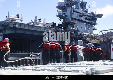 LES marins DE LA MER DES PHILIPPINES (18 juin 2022) manipulent des lignes lors d'un réapprovisionnement en mer avec le porte-avions de la classe Nimitz USS Abraham Lincoln (CVN 72) à bord du croiseur à missiles guidés de la classe Ticonderoga USS Mobile Bay (CG 53). Abraham Lincoln Strike Group est en cours de déploiement prévu dans la zone d'exploitation de la flotte américaine 7th afin d'améliorer l'interopérabilité par le biais d'alliances et de partenariats tout en servant de force d'intervention prête à l'emploi pour soutenir une région Indo-Pacifique libre et ouverte. (É.-U. Photo marine par Spécialiste communication de masse 3rd classe Alonzo Martin-Frazier) Banque D'Images