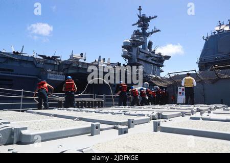 LES marins DE LA MER DES PHILIPPINES (18 juin 2022) manipulent des lignes lors d'un réapprovisionnement en mer avec le porte-avions de la classe Nimitz USS Abraham Lincoln (CVN 72) à bord du croiseur à missiles guidés de la classe Ticonderoga USS Mobile Bay (CG 53). Abraham Lincoln Strike Group est en cours de déploiement prévu dans la zone d'exploitation de la flotte américaine 7th afin d'améliorer l'interopérabilité par le biais d'alliances et de partenariats tout en servant de force d'intervention prête à l'emploi pour soutenir une région Indo-Pacifique libre et ouverte. (É.-U. Photo marine par Spécialiste communication de masse 3rd classe Alonzo Martin-Frazier) Banque D'Images