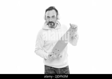 homme heureux écouter de la musique dans les écouteurs tenir penny skateboard isolé sur blanc, culture du skateboard. Banque D'Images