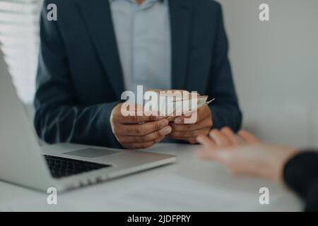 Homme d'affaires donnant de l'argent à son partenaire tout en faisant le contrat - les concepts de corruption Banque D'Images
