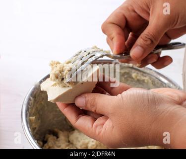 Processus de cuisson, tofu farci avec pâte de poisson faisant Baso Tahu Goreng (Batagor) ou Siomay Bandung, populaire Street Food en Indonésie. Une femme main usi Banque D'Images