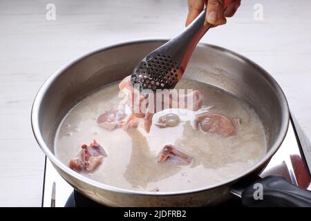 Indonésie Accueil processus de cuisson, main femelle Ajouter le bâton de poulet à l'aide de pinces, faire de l'indonésien ou de la thaïlandaise style curry, traditionnel comme Banque D'Images