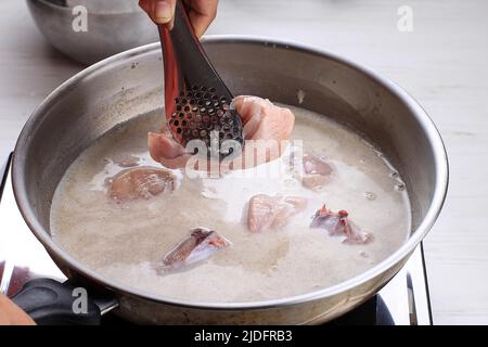 Indonésie processus de cuisson à la maison, main femelle Ajouter le poulet à la poêle à l'aide de pinces, faire le curry indonésien ou thaïlandais, appel gastronomique asiatique traditionnel Banque D'Images