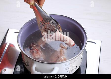 Indonésie Accueil processus de cuisson, main femelle Ajouter le bâton de poulet à l'aide de pinces, faire de l'indonésien ou de la thaïlandaise style curry, traditionnel comme Banque D'Images