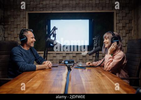 Une jeune femme hôte parle au microphone et interroge un homme pour un podcast radio. Banque D'Images