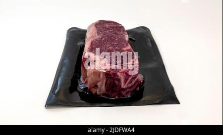 morceau de bœuf cru pour steak dans un emballage sous vide isolé sur fond blanc Banque D'Images