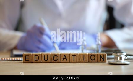 Gros plan de l'éducation de mot collectée de cubes en bois dans brut. Médecin en uniforme médical écrivant l'information. Concept d'éducation médicale Banque D'Images
