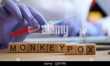 Gros plan de mots singe varicelle collectée de cubes en bois. Infirmière tenant la seringue d'injection en main. Concept de la maladie virale, du vaccin et de la vaccination Banque D'Images