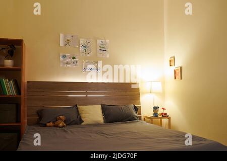 Chambre vide de préadolescent avec lampe de nuit sur la table de chevet et dessins suspendus au-dessus du lit Banque D'Images