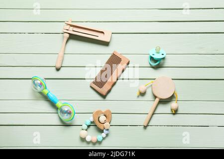 Peigne à cheveux pour bébé et différents accessoires sur fond en bois vert Banque D'Images