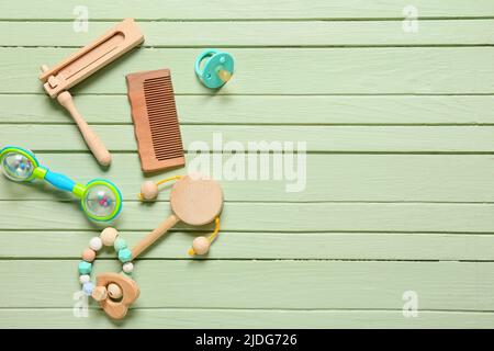 Peigne à cheveux pour bébé et différents accessoires sur fond en bois vert Banque D'Images