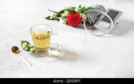 une tasse de thé avec fleur de jumine et moniteur de tension artérielle, boisson contre la pression cardiaque, foyer sélectif, espace de copie dans le coin droit Banque D'Images